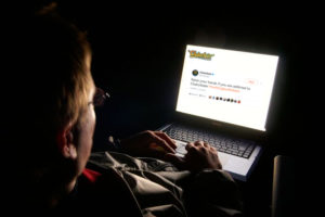 A man sits on a laptop in the night researching his pornography addiction.